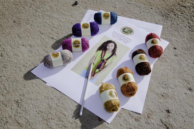 tiny balls of rainbow yarn laid on top of pattern with crochet hook