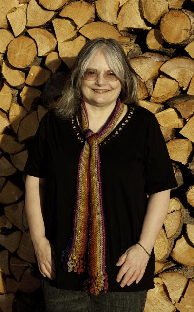 lady black top with dark rainbow scarf, split wood in background