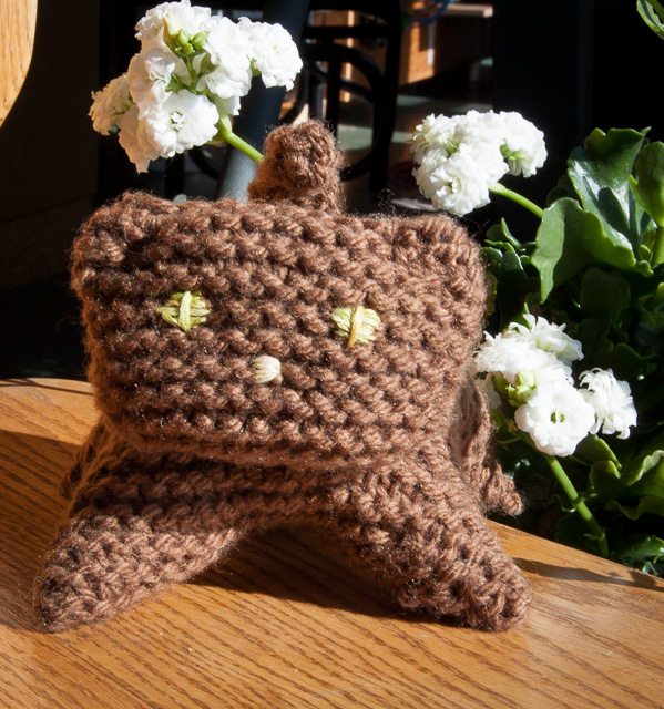 close-up:brown knit kittens face with yellow/green eyes